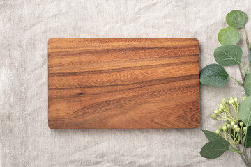Wooden board and plant on linen table cloth