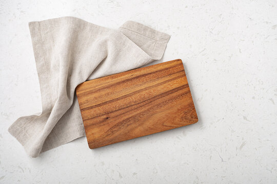 Wooden cutting board with linen napkin on marble table