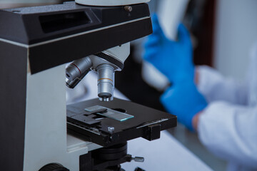 medical or scientific researcher researching and experimenting Multi-colored solution, vial and microscope In the laboratory or in the laboratory by wearing blue gloves and white clothing completely.