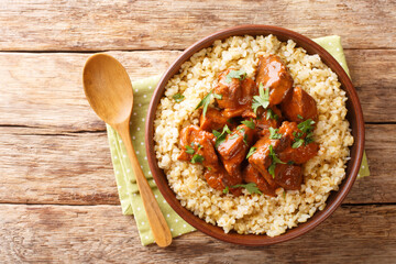 Slowly braised pork in red wine served with bulgur close-up in a bowl on the table. horizontal top view from above