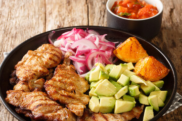 Poc chuc is a Mexican meat dish consisting of thin pork cutlets marinated in orange juice closeup in the plate on the table. Horizontal