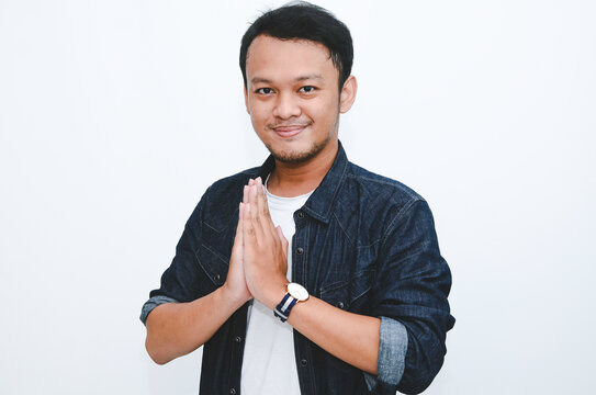 Young Asian man wearing give greeting hands. Indonesian man on grey background.