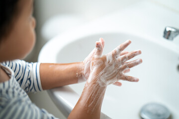 Small child washing her hands with soap in the sink. - obrazy, fototapety, plakaty