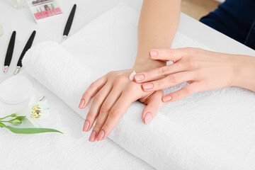 Woman with beautiful manicure applying cream onto hands in salon