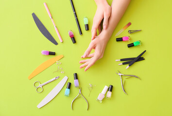 Female hands and professional tools for manicure on color background
