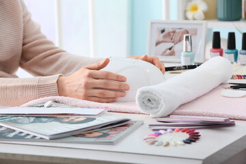 Woman with lamp for drying gel nail polish in beauty salon