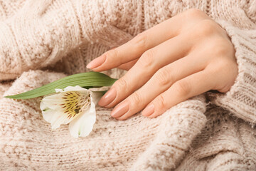 Woman with beautiful manicure holding flower, closeup