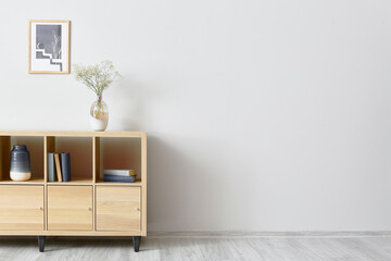 Modern chest of drawers with decor near light wall