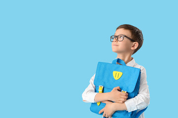 Little schoolboy with backpack on color background