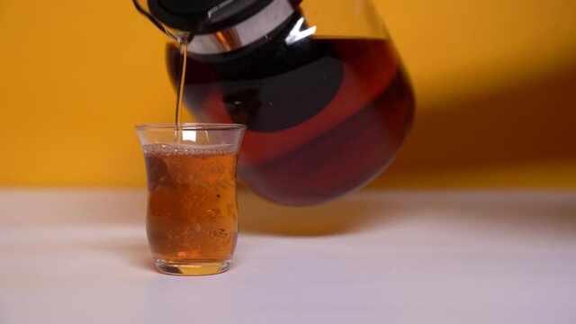 Black tea is poured from a teapot into a armudu glass. Traditional tea serving in the countries of the East in armudu glasses. Traditional Turkish Tea Party.