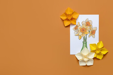 Origami narcissus flowers and greeting card on color background