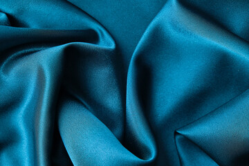 Blue silk drapery and upholstery fabric from the courtyard. Blue satin, silky fabric, wave, draperies. Beautiful textile backdrop. Close-up. Top view