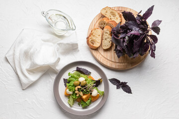 Composition with tasty fresh salad, bread and jug of oil on light background