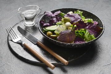 Plate with tasty fresh salad and jug of oil on dark background, closeup