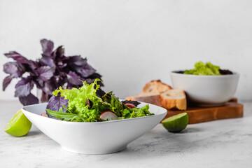Bowl with tasty fresh salad on light background, closeup