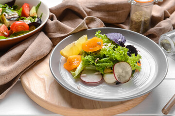Plate with tasty fresh salad on light wooden background, closeup