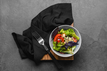 Bowl with tasty fresh salad on dark background