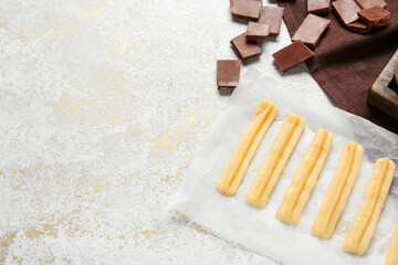 Uncooked churros and chocolate on light grunge background