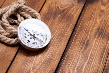 Compass and rope on wooden texture background