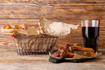 Tasty churros with glass of cola on wooden background