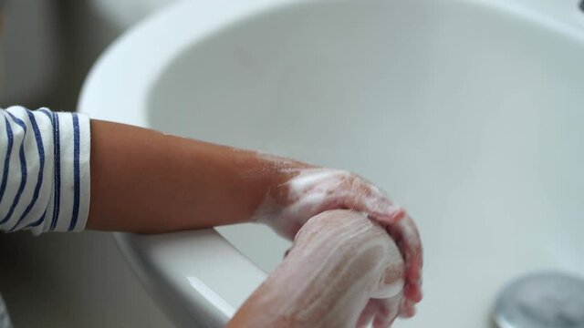 Small girl washing her hands with soap in the sink. Hygiene concept.