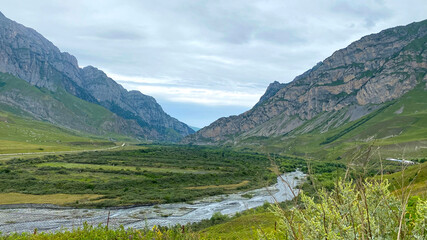 Obraz premium Mountain river of the village of Dargavs. Beautiful panorama of green alpine meadows