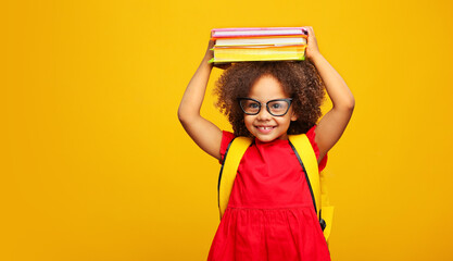 funny smiling Black child school girl with glasses hold books on her head