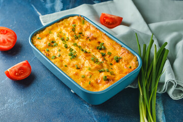 Casserole with mashed potatoes and tomato on color background