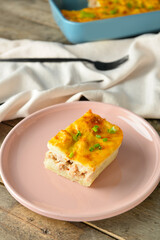 Plate with piece of mashed potato casserole on wooden background, closeup