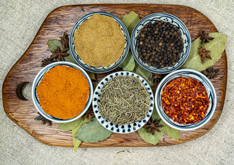 Spices in a wooden board - Curry powder, black pepper, paprika, rosemary, chilli flakes
