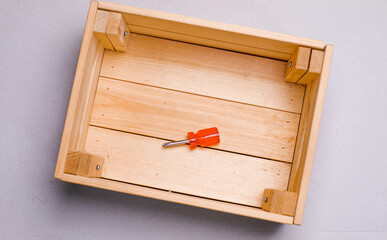 brown wooden box on a white background with a red phillips screwdriver background texture.the...