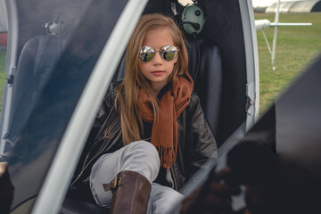 Fototapeta na wymiar Tween girl in mirrored sunglasses sitting in open helicopter