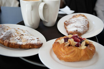 an almond croissant and a bun with strawberry slices lie on a white plate next to a white cup of coffee cappuccino and latte food fresh pastries bakery handmade kitchen cafe breakfast health