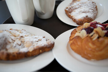 an almond croissant and a bun with strawberry slices lie on a white plate next to a white cup of coffee cappuccino and latte food fresh pastries bakery handmade kitchen cafe breakfast health