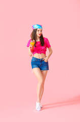 Beautiful young woman with cocktail on color background
