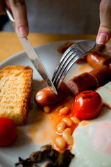 a girl with a knife and fork eats an English breakfast fresh tomatoes scrambled eggs fried eggs with rye white fresh bread and meat sausage pork sausage meat food tomorrow lunch meal health