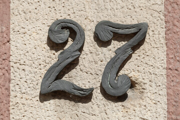 Hausnummernschild Nummer Siebenundzwanzig auf einer hellen Hausmauer, Deutschland, Europa