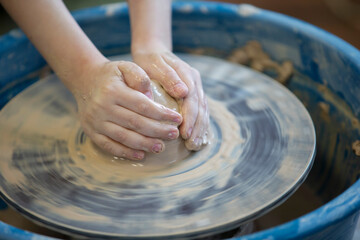 Close-up of a potter's hands with an item on a potter's wheel. Working with clay. Clay workshop. Craft training.