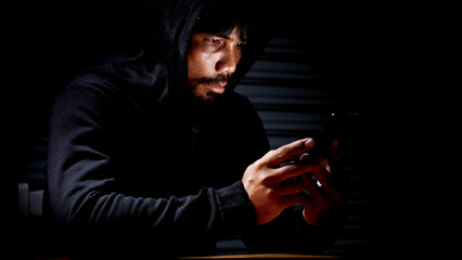 Mysterious man in hoodie on dark background. Dangerous criminal. Silhouette of man in the hood,...