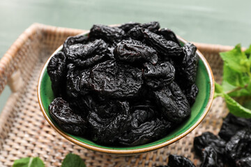 Bowl with tasty prunes on table, closeup