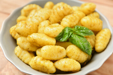 Bowl with tasty pesto gnocchi on table, closeup