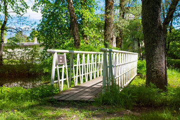 A white wooden bridge in the Poltsamaa city park (Estonian - Põltsamaa) on a sunny summer day.