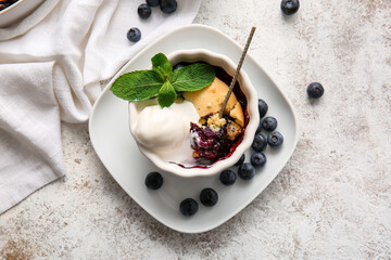 Ramekin with blueberry cobbler and ice cream on light background