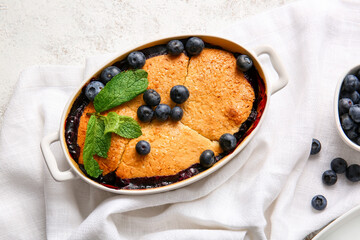 Baking dish with blueberry cobbler on light background