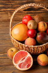 Basket with fresh fruits on wooden background, closeup