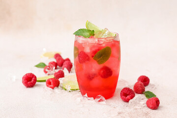 Glass of cold lemonade with raspberry on light background
