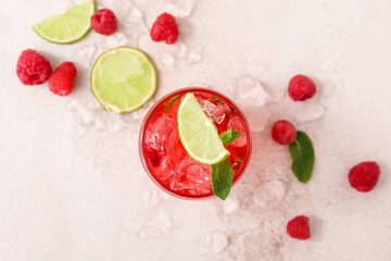 Glass of cold lemonade with raspberry on light background