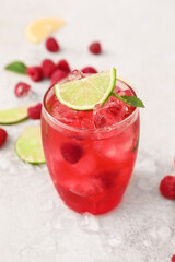 Glass of cold raspberry lemonade on light background