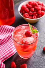 Glass of tasty raspberry lemonade on dark table