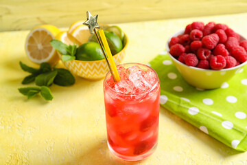 Glass of delicious raspberry lemonade on color background
